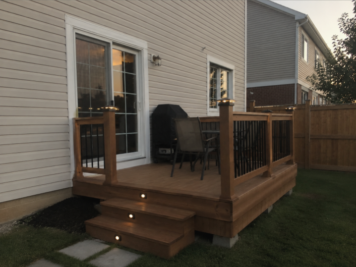 Backyard wood deck with railing lights at dusk